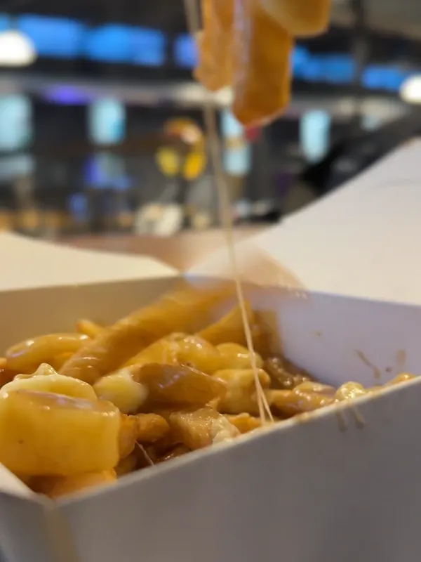 Cheese curds stretching from a forkful of Motorburger poutine